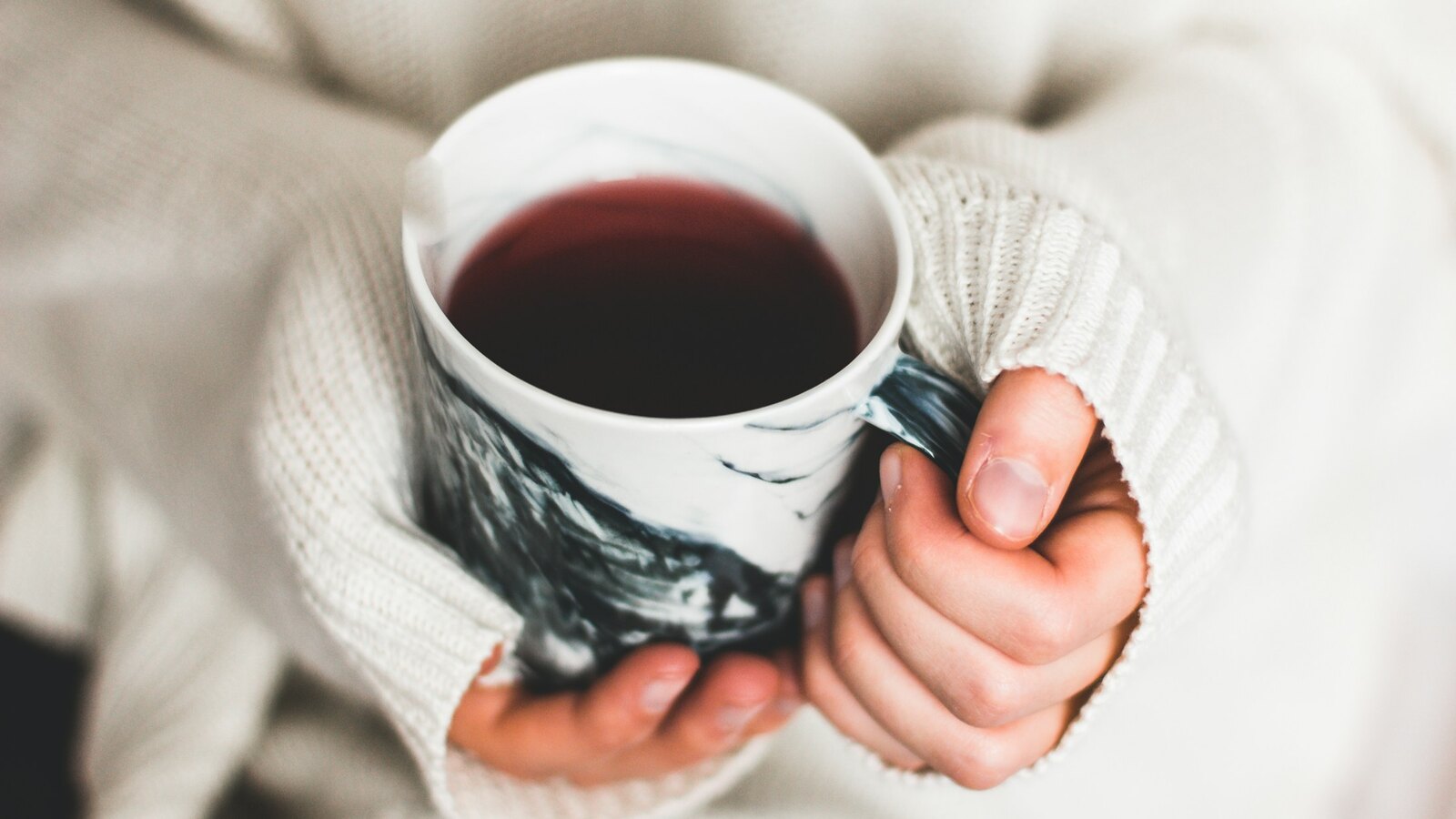 Warm hands cradle a cup of herbal tea